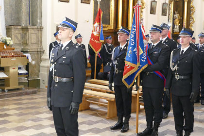 strażacy w mundurach stojący ze sztandarami w kościele