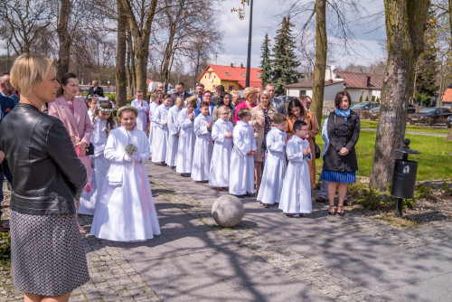 grupa dzieci w albach wraz z rodzicami stojąca przed kościołem