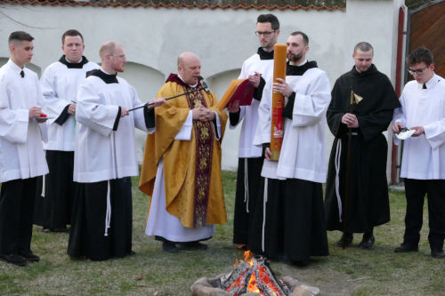Kapłan dokonujący poświęcenia ognia oraz Paschału w asyście kilku ministrantów oraz zakonników.