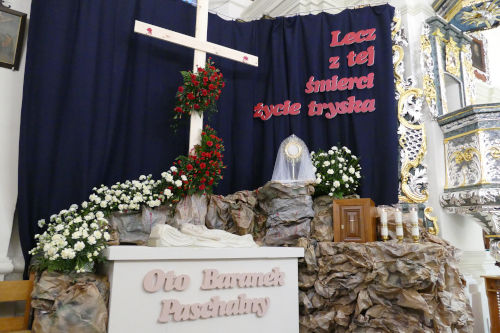 GrĂłb PaĹski - na imitacji skaĹy postawiony jest NajĹwiÄtszy Sakrament. Po lewo figura Jezusa pod krzyĹźem przyozdobionym kwiatami.