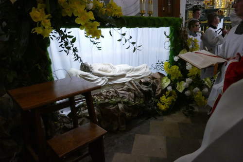 Figura Jezusa zĹoĹźonego w grobie. Po prawej stronie ministranci oraz KapĹan trzymajÄcy KsiÄgÄ.